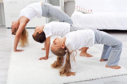 Woman And Kids Doing Bridge Stretch Gymnastic Exercises At Home