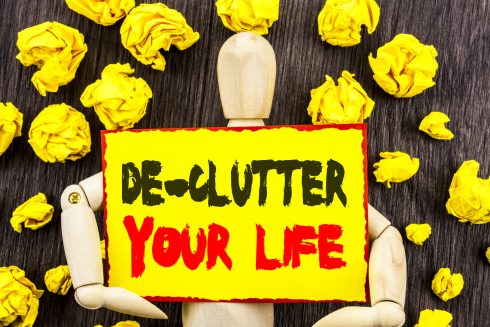 Announcement Text Showing De Clutter Your Life  Concept Meaning Free Less Chaos Fresh Clean Routine Written On Sticky Note Holding By Sculpture On The Wooden Background