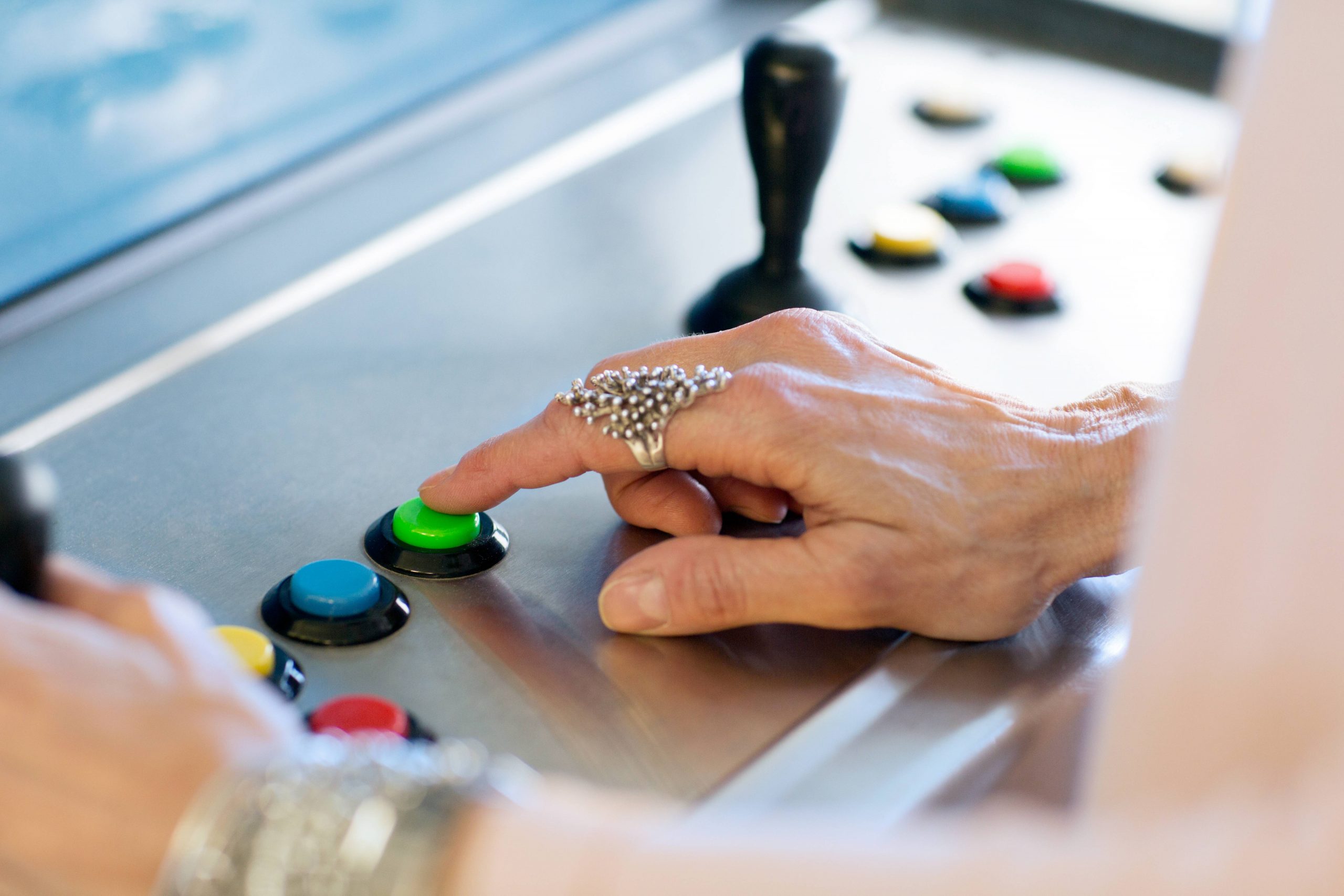Close Up Of Senior Womans Hand Pressing Button On Games Machine