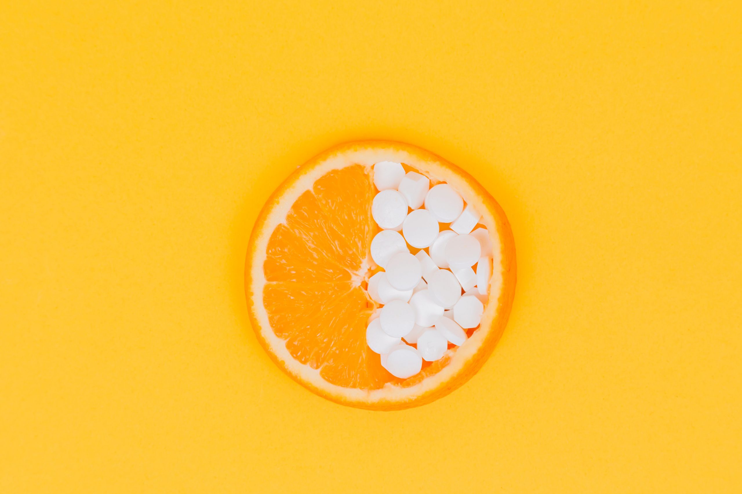 The Close Plan. A Slice Of Orange, Lemon Lies Half Filled With Pills, Vitamins On A Yellow, Orange Background. Vitamin C. Medicine. Creativity. Vitamins. Pills. Place For An Inscription. Advertising.