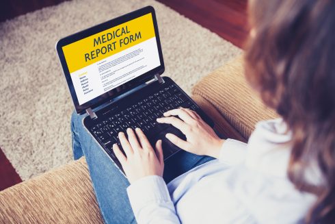 Woman Fill In A Medical Report Form With A Laptop At Home.
