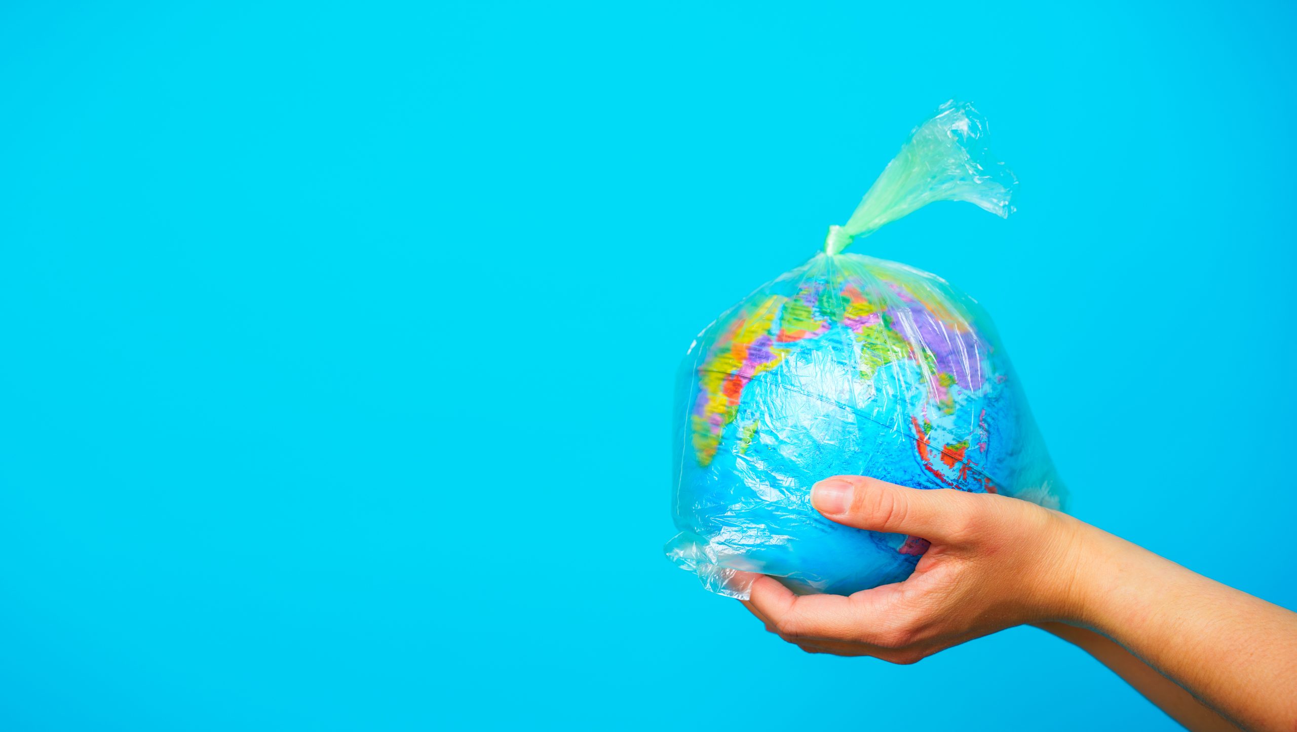 Woman Holds In Hands Plastic Bag With Planet Earth At Blue Background. The Concept Of Plastic Pollution.