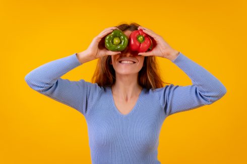 Vegetarian Woman In A Portrait With Peppers In Her Eyes On A Yel