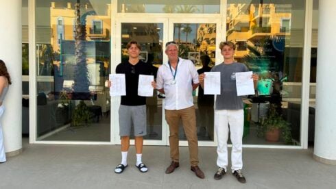 Three people pose outside a school door