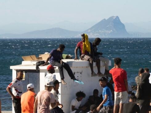 A group of migrants sit on a concrete structure in Ceuta