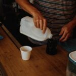 A woman pouring bleach into a cup
