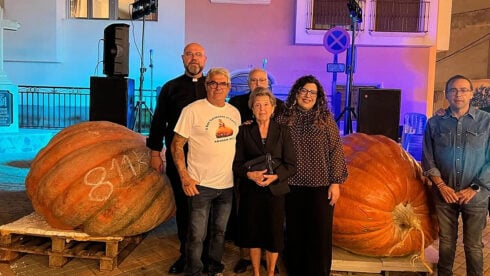 A group of people pose with two giant pumpkins