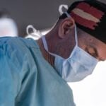 Alex Aslani during surgery in scrubs and a mask